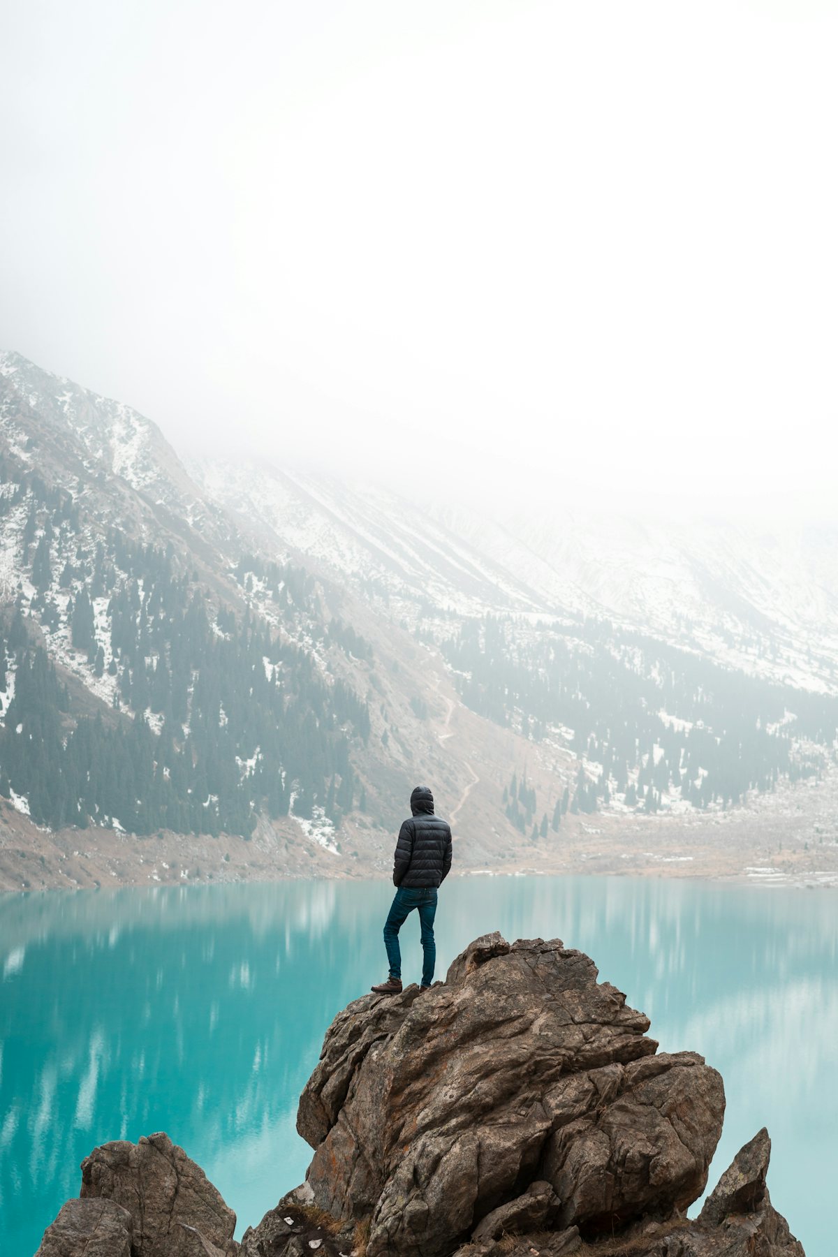 A traveller standing on a rock above Big Almaty Lake, Kazakhstan
